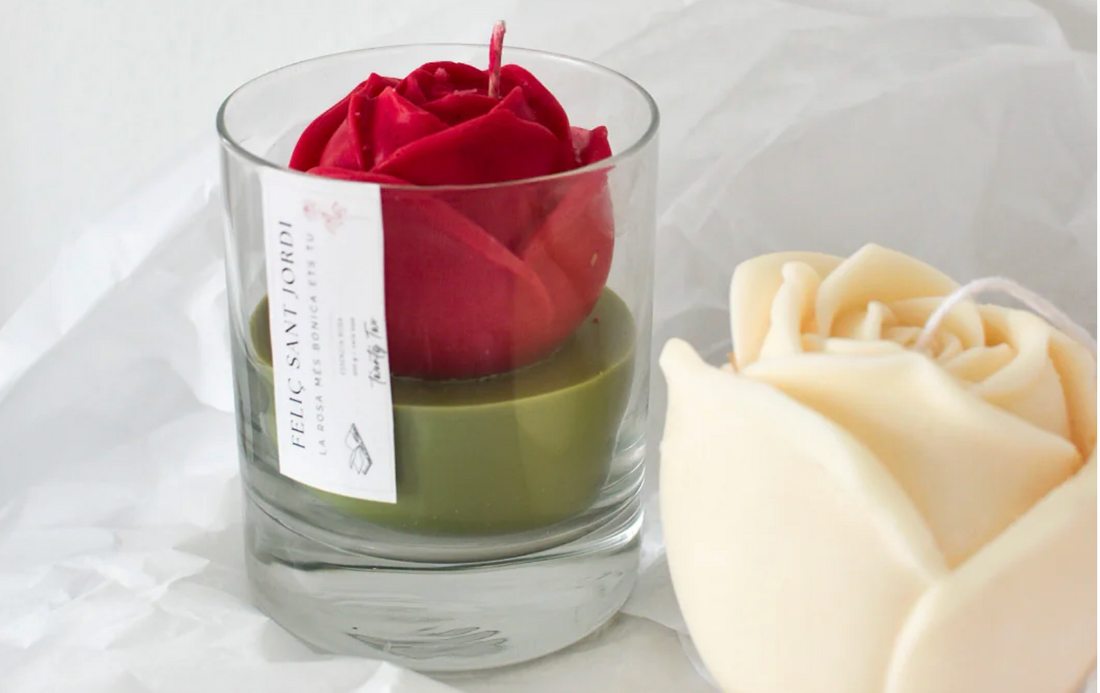 Vela artesanal en forma de rosa roja para Sant Jordi en tarro de cristal con etiqueta de Twentytwo, junto a una rosa vela en color crema